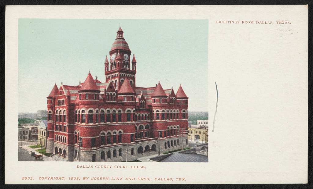 Color postcard of a red stone courthouse with a tall central clock tower, round corner turrets under conical roofs and a gray stone ground floor, a horse and buggy at lower left, printed with the words Greetings from Dallas, Texas.