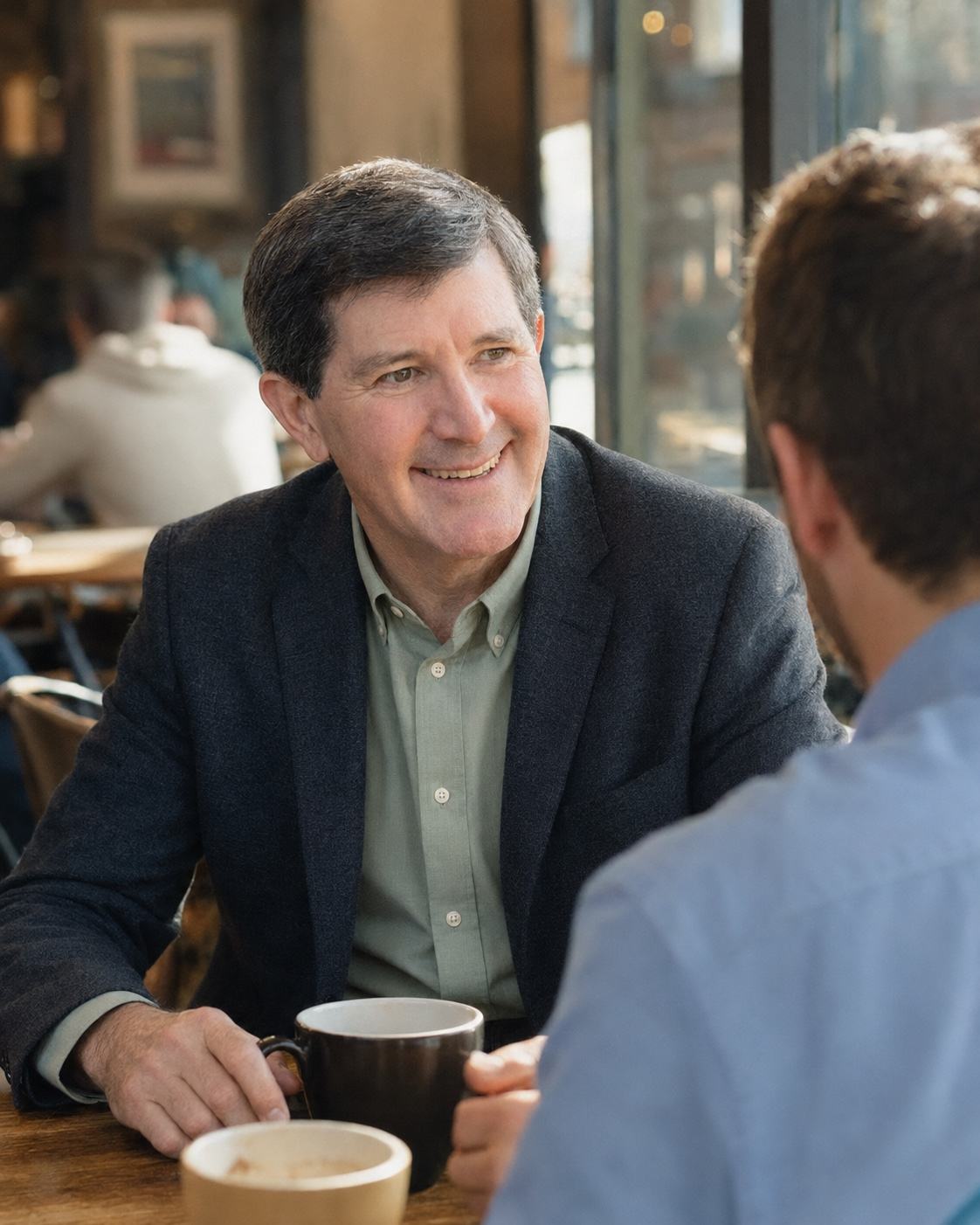 Smiling across a cafe table with a coffee cup in hand